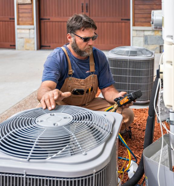 A technician in front of an AC unit performing a series of tests with a handheld device