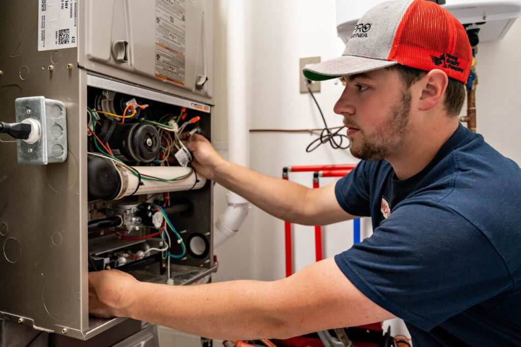 An image of a modern furnace with a technician in a work uniform checking it.