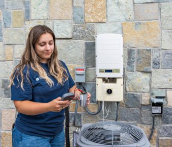 A woman holding a tester next to an AC unit