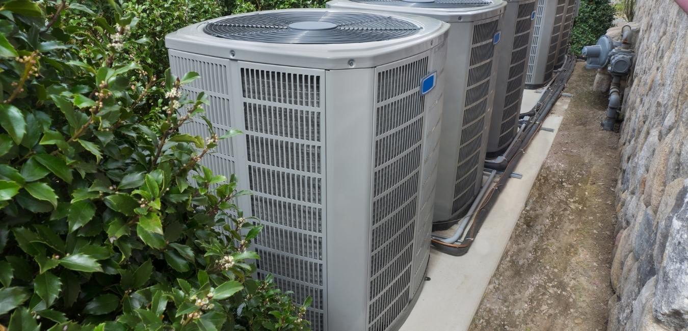 Three central air conditioner units on the side of a building