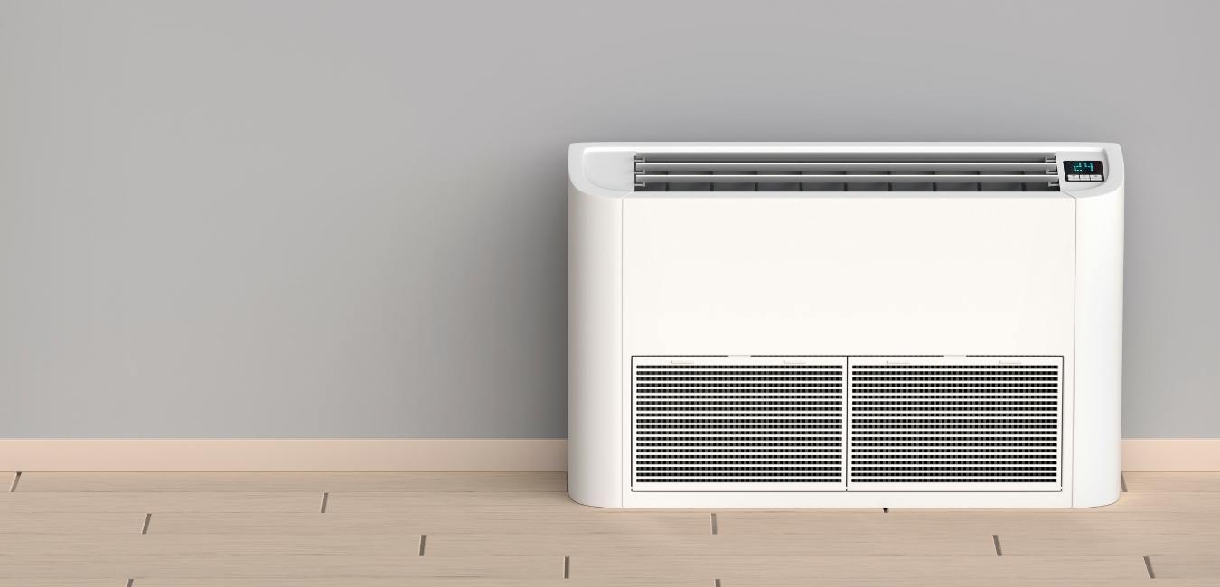 A white air conditioner unit mounted to a wood floor